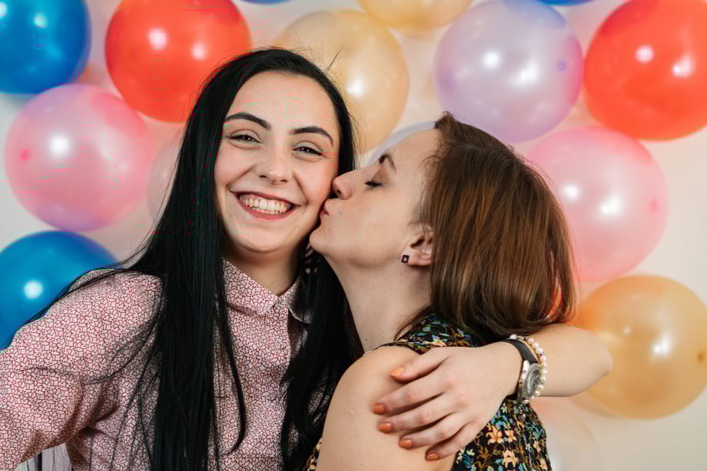 Kaksi naista juhlii, taustalla ilmapalloja.