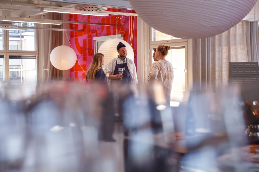 Tapahtumakeittiön kuvituskuvaa. Blurrib taustan takana kolme henkilö juttelee.