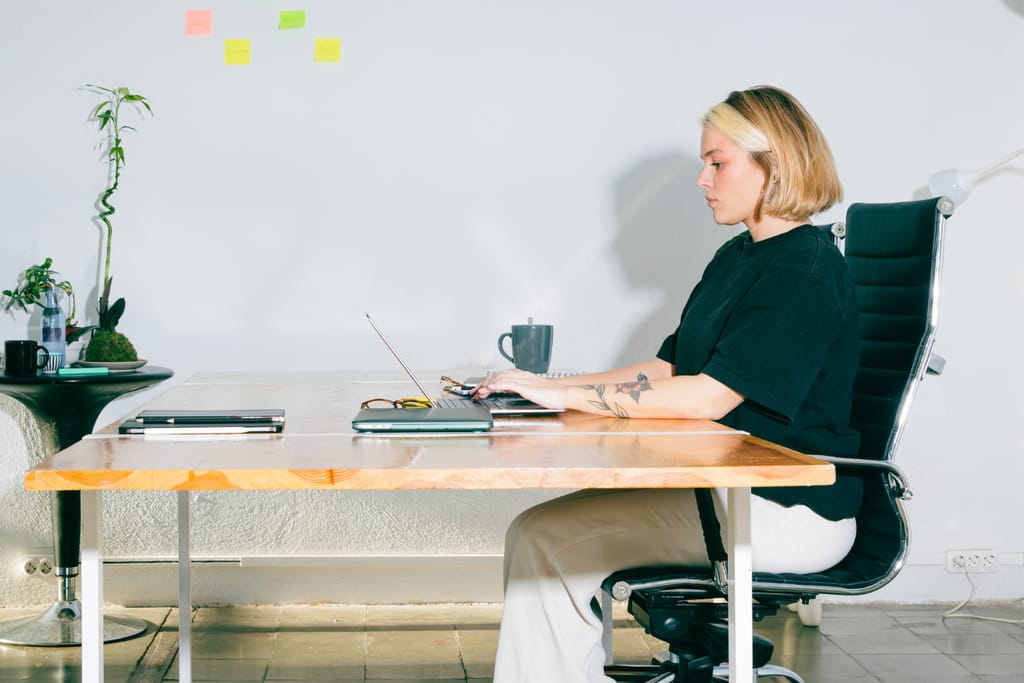 Nainen työskentelee tietokoneella toimistopöydän ääressä.