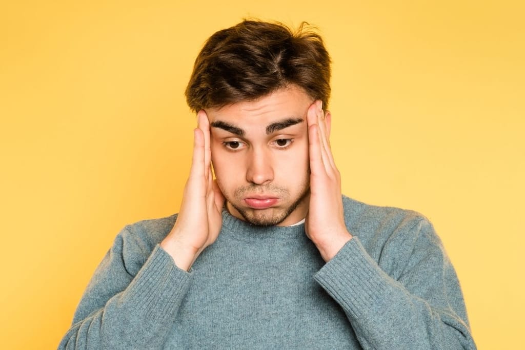 Stressaantunut mies pitää päätään käsissään jatkuvan suorittamisen ja uupumuksen keskellä
