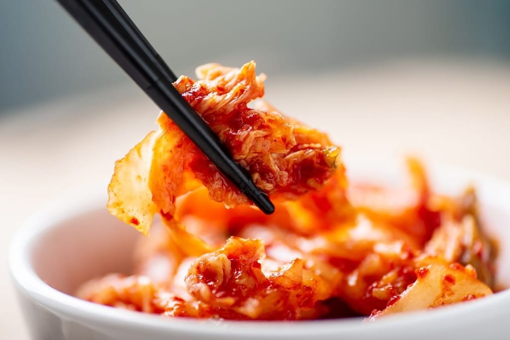 Kimchi lähikuva – kirpeä korealainen fermentoitu kaali syömäpuikoissa