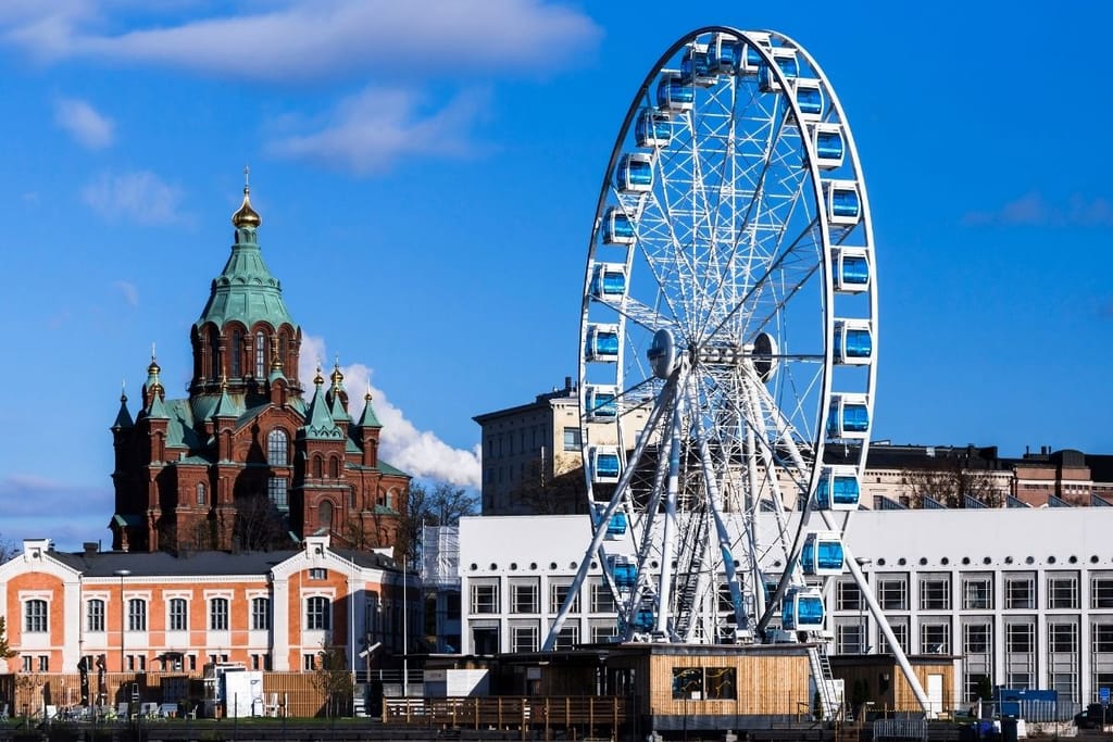 Helsingin sataman näköala aurinkoisena päivänä — etualalla valkoinen maailmanpyörä ja taustalla Uspenskin katedraali