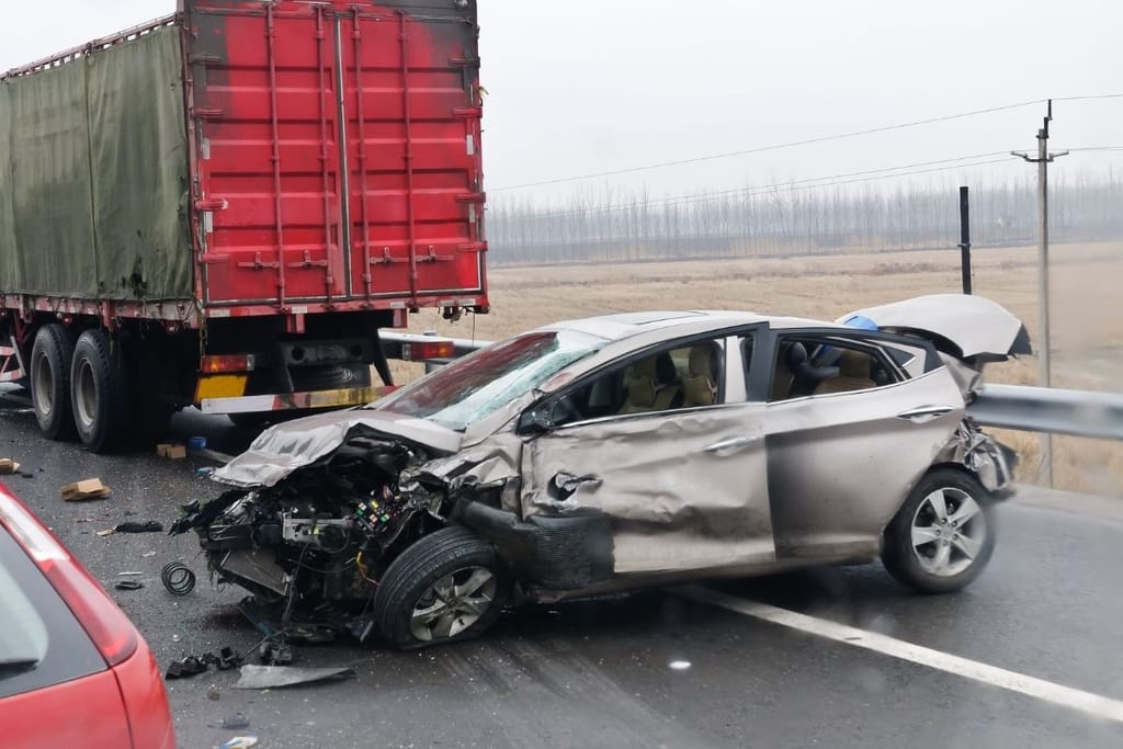 Vakavasti vaurioitunut henkilöauto liikenneonnettomuuden jälkeen tien laidassa rekka-auton vieressä