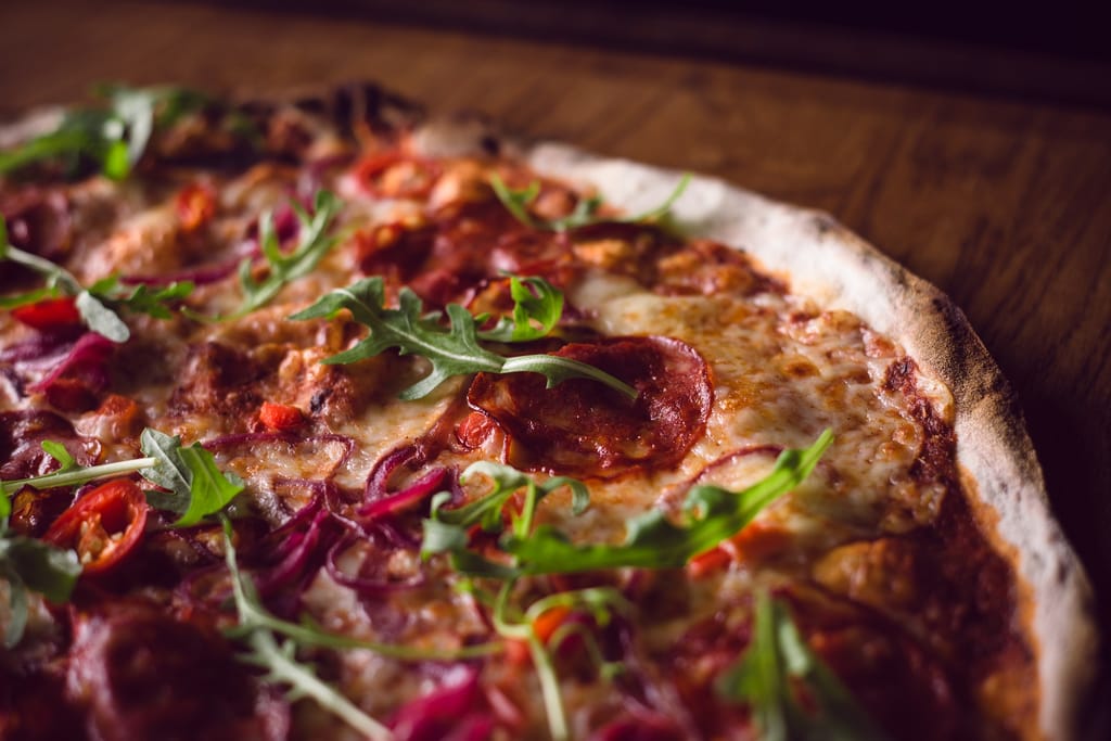 Lähikuva pizzasta, jonka päällä on rucolaa.