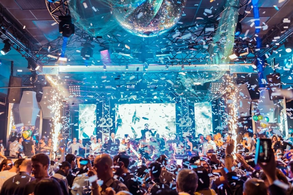 Täynnä oleva yökerho konfettisateessa ja discopallolla 2000-luvun bileiden tunnelmassa
