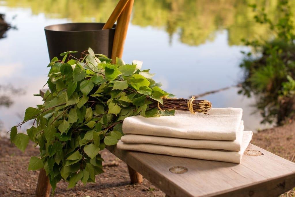 Saunavihta, pyyhkeet ja järvimaisema suomalaisessa mökkiympäristössä havainnollistavat mökkeilyn terveysvaikutuksia.