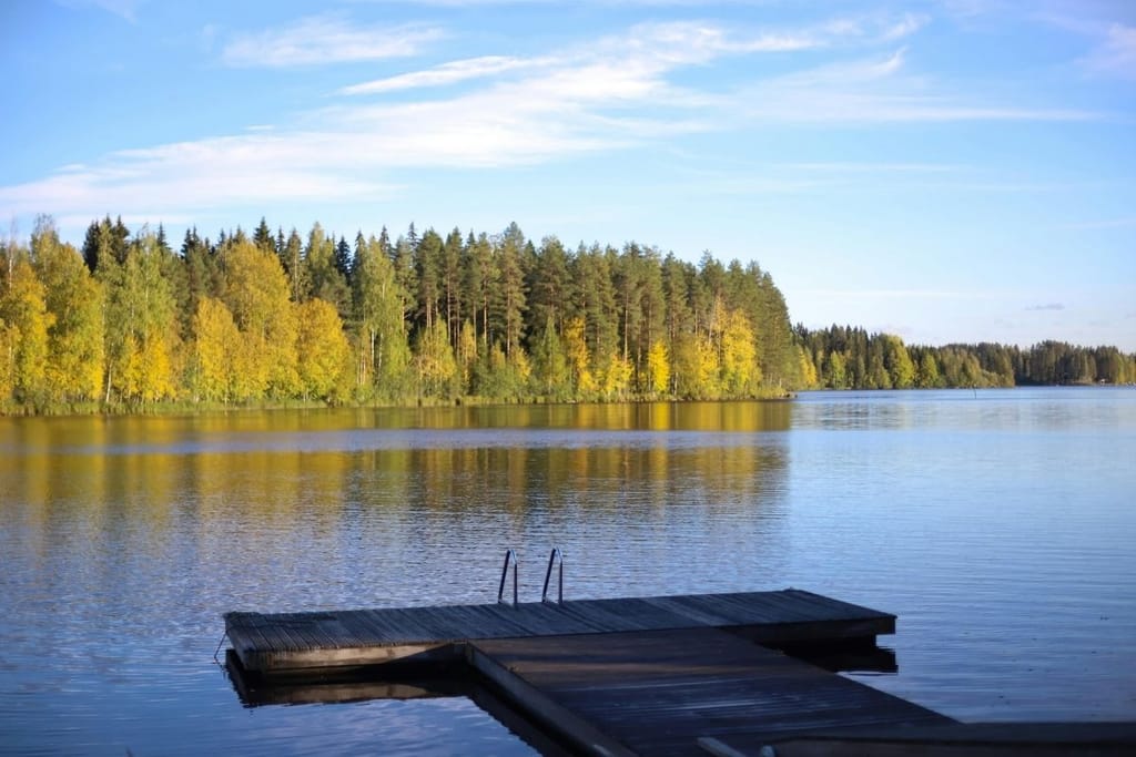 Tyyni suomalainen järvimaisema ja uimalaituri — Suomi on onnellisin maa tilastoissa mutta paradoksi piilee pinnan alla