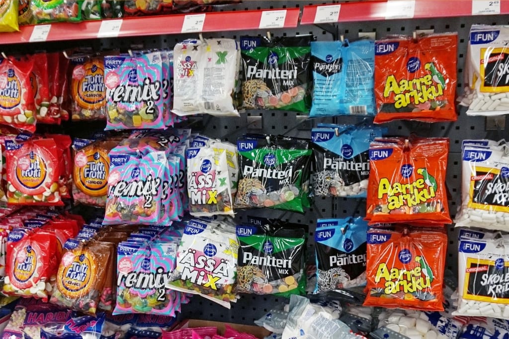 Ruokakaupan karkkihylly täynnä erivärisiä Fazerin ja muiden valmistajien makeispusseja rivissä.