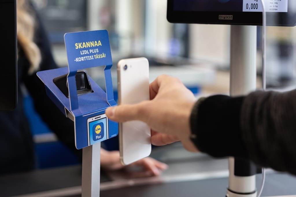 Asiakas skannaa puhelintaan Lidl Plus -lukijaan kaupan kassalla.
