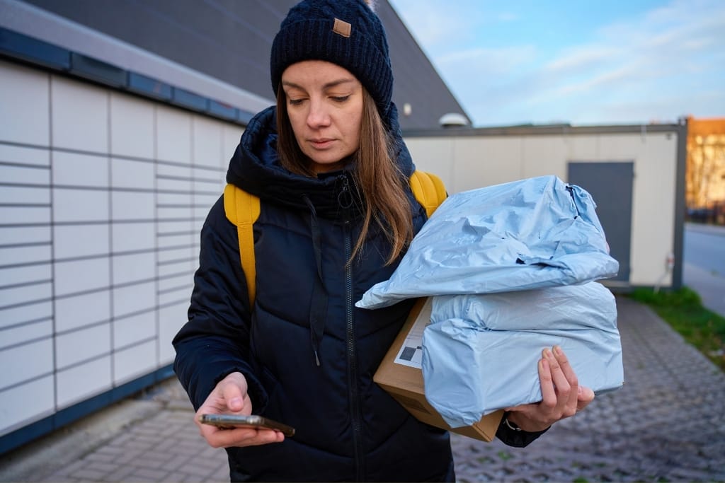Nainen kantaa verkkokaupasta tilattuja paketteja