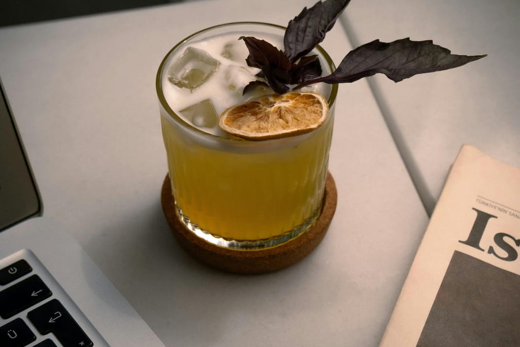 Cocktaili pöydällä. Vieressä kannettava tietokone ja sanomalehti.
