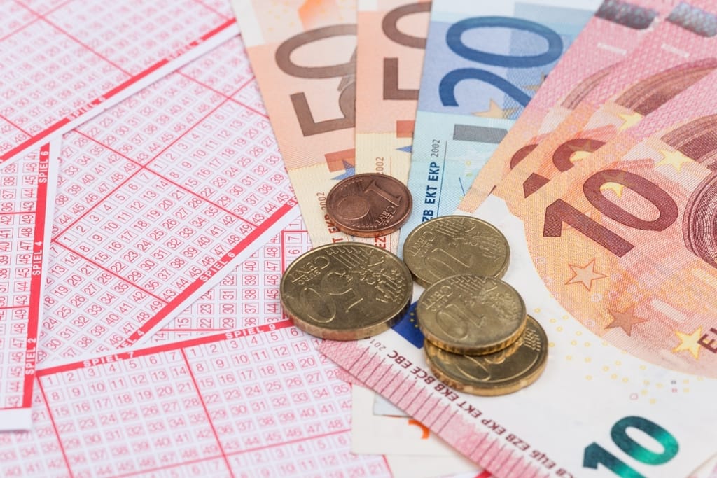 urojackpot-pelikuponki, euroseteleitä ja kolikoita vaalealla alustalla.