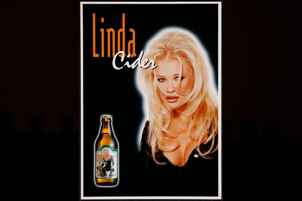 Vanha Linda Cider -mainos, jossa on vaaleahiuksinen nainen ja Linda Cider -pullo.