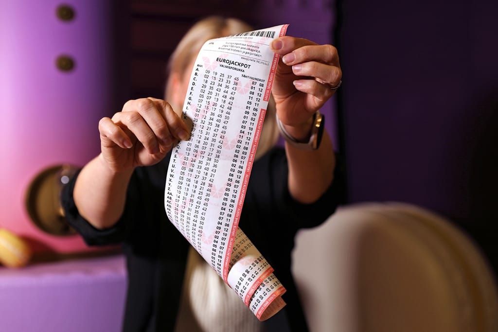 Henkilö pitelee käsissään pitkää Eurojackpot-pelikuponkia.