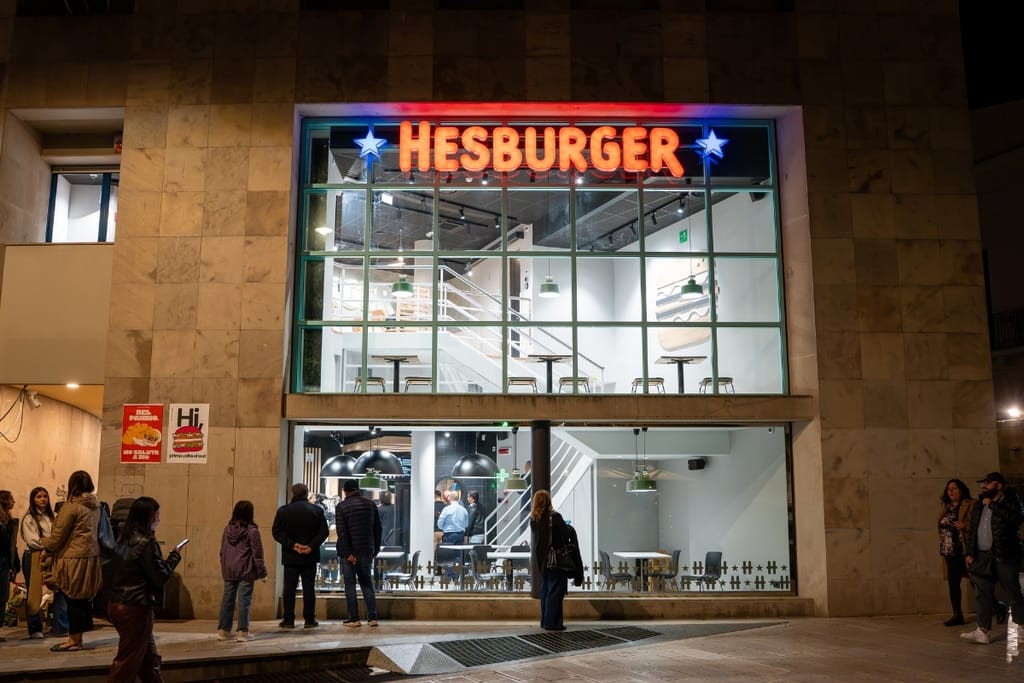 Hesburgerin ensimmäinen ravintola Italiassa, Materan kaupungissa, valaistuna ilta-aikaan ihmisten seistessä sen edustalla.