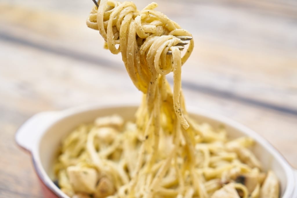 Haarukkaan kierrettyä pastaa nostetaan kermaisesta pasta-annoksesta.