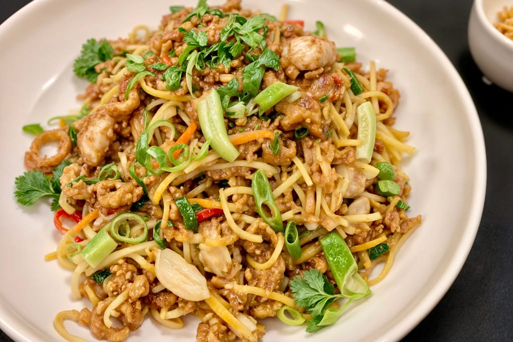 Kulhollinen wokkiperunaa, jossa on kanaa, kasviksia, kevätsipulia ja yrttejä.