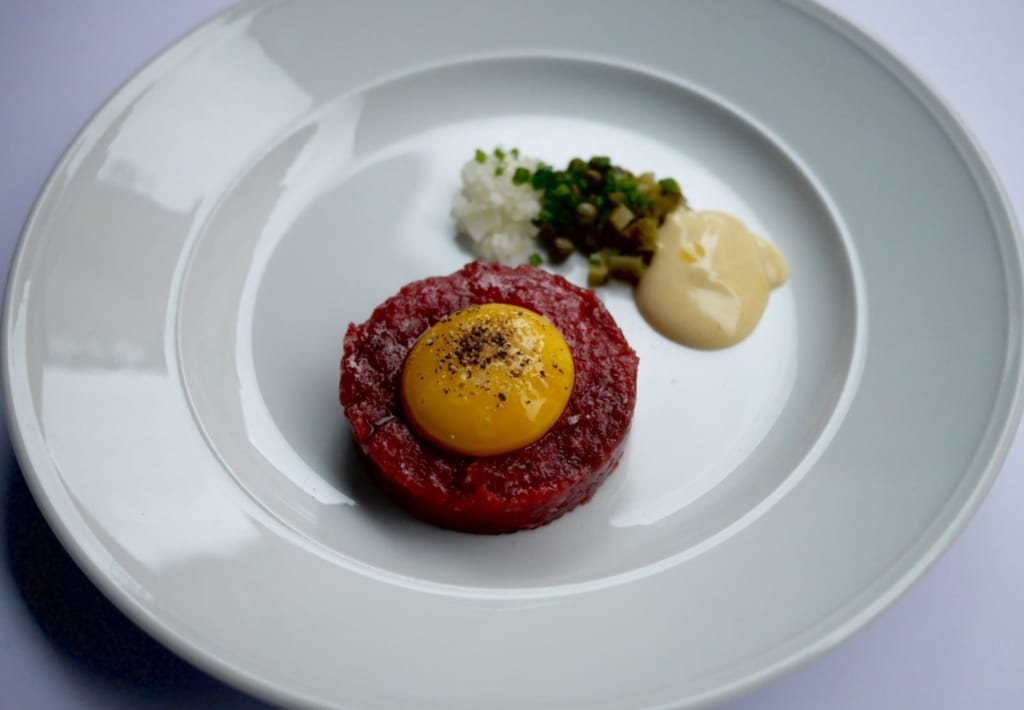 Ravintola-annos tartaria, jonka päällä raaka kananmunan keltuainen.