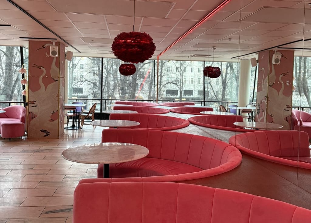 Ravintola Biblosin vaaleanpunainen sisustus: kaarevia samettisohvia, pyöreitä pöytiä ja suuria ikkunoita puiston suuntaan.