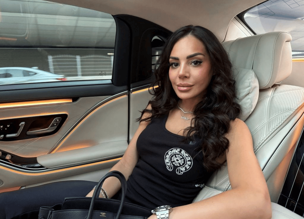 Sofia Belórf istuu mustassa toppipaidassa luksusauton takapenkillä, vaaleat nahkaverhoilut ja oranssi ambient-valaistus.