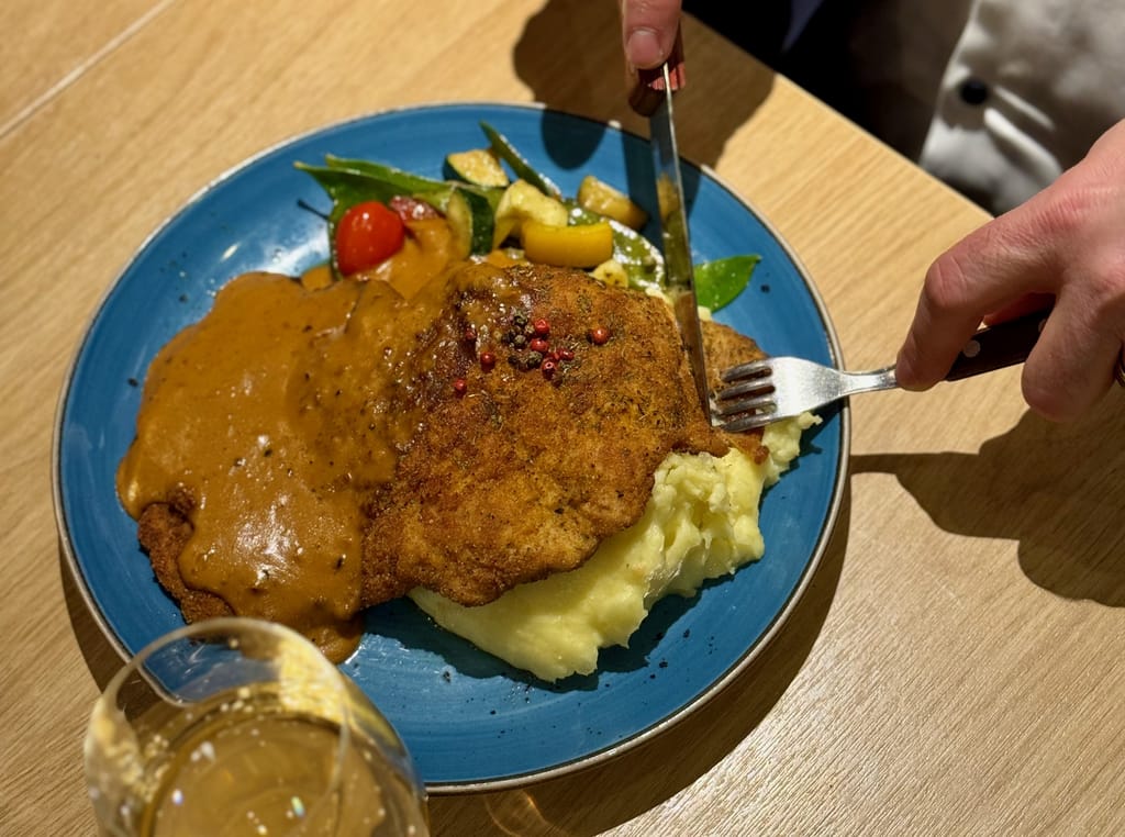 Henkilö leikkaa haarukalla ja veitsellä lautasella olevaa pihviä.