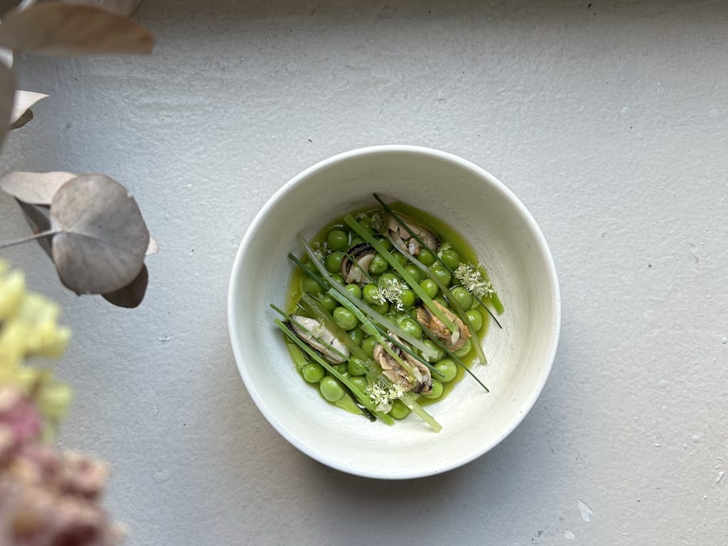 Ravintola Wellamon herneistä ja simpukoista koostuva annos valkoisessa kulhossa.