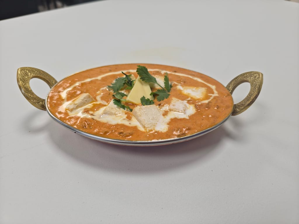 Intialainen kana-annos kermaisessa tomaatinkastikkeessa koristeellisessa tarjoiluastiassa.