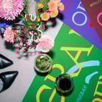 Viinilasit ja kukkakimppu värikkäiden Tales-viinibaarin julisteiden päällä.