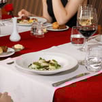 kampasimpukka-annos ravintolapöydällä. Vieressä lasi punaviiniä ja vesilasi.