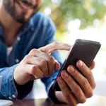 Mies käyttää älypuhelinta käsissään – lähikuva somen selaamisesta