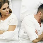 Pariskunta riidan jälkeen sängyssä selin toisiinsa – etäinen tunnelma