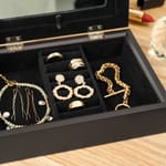 Avoin korurasia, jossa on sormuksia, korvakoruja, rannekoru ja kaulakoru siististi lokeroituna.