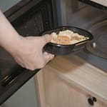 Mies laittaa valmisruokaa mikroaaltouuniin.