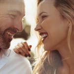 Rakastunut pariskunta katsoo toisiaan silmiin ja hymyilee.