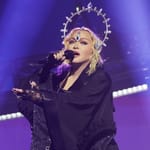 Madonna esiintyy lavalla mustassa asussa ja sädekehämäisessä päähineessä mikrofonin kanssa