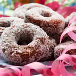 Munkkeja pöydällä lautasella. Vieressä serpentiiniä.