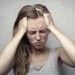 ahdistunut nuori nainen pitelee päätään stressin ja ahdistuksen keskellä