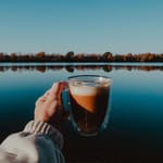 kahvikuppi kädessä järvimaisemassa aamukahvi ulkona kahvin vaikutus kehoon