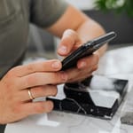 Kädet selaavat älypuhelinta – jatkuva skrollaaminen voi kuormittaa kehoa huomaamatta