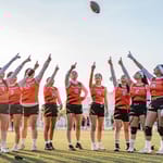 naisten urheilujoukkue kentällä juhlistaa peliä auringonlaskussa