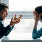 Pariskunta riitelee pöydän ääressä – mies huutaa ja nainen peittää kasvonsa käsillä