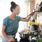 Nainen kokkaa keskittyneesti keittiössä – flow-tila tekee ruoanlaitosta sujuvaa