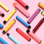Värikkäitä kertakäyttöisiä vape-laitteita levitettynä pöydälle – nuorten suosima sähkösavuketrendi
