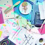 Sotkuinen työpöytä täynnä muistilappuja, kahvikuppeja ja tavaroita – luova kaaos ja epäjärjestys