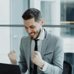 työelämä menestys ura eteneminen toimistossa mies juhlii läppärin äärellä