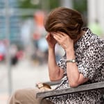 yksinäinen nainen istuu penkillä kaupungissa – yksinäisyys kaupungeissa kasvaa