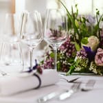 Ravintolapöytä, jossa kukkia ja kattaus.