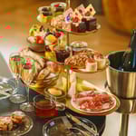 Runsas brunssitarjoilu kerrostarjottimella, kuohuviiniä ja erilaisia herkkuja pöydällä.