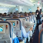 Lentokoneen matkustamo täynnä matkustajia – lentokoneetiketti ja käytöstavat lennolla puhuttavat