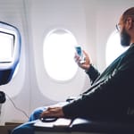 Mies selaa puhelinta lentokoneessa.